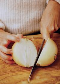 Gripping the onion and with fingertips curved, slice in half from the root end straight