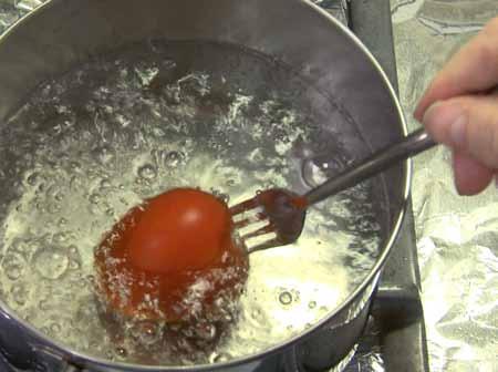 2 Pierce each tomato with a fork and hold it under boiling water for about 10 seconds.