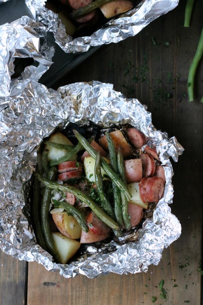 potatoes, sausage, onions and green beans to center of the foil Close up the sides of the foil Add 1 tablespoon of unsalted butter to the top of each package Season with either a tablespoon of