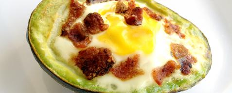 Crack an egg into each half of the avocado, resting the edge of the avocado on the side of the cookie sheet to help keep the avocado steady. Top with bacon crumbs.