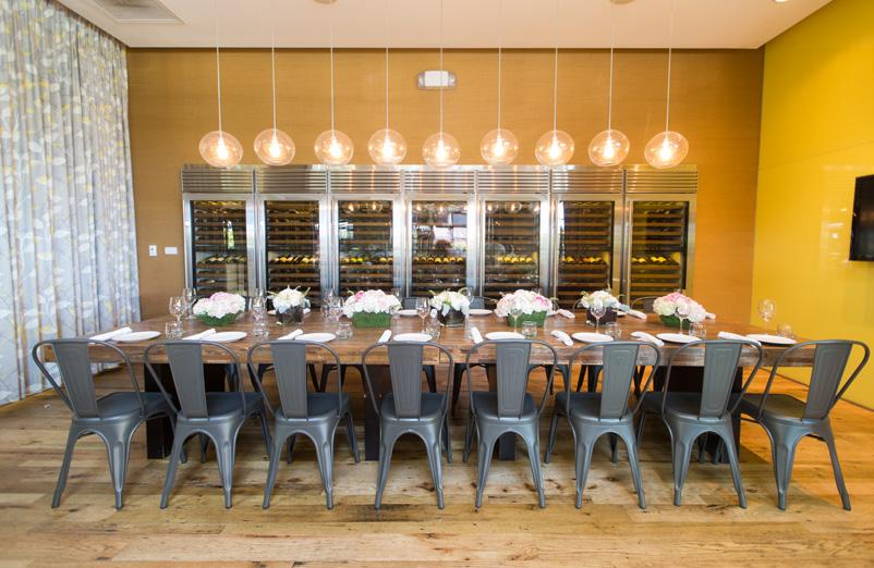 Seven Sub-Zero wine cases line the back wall and floor-to-ceiling glass walls on two sides enclose the space.