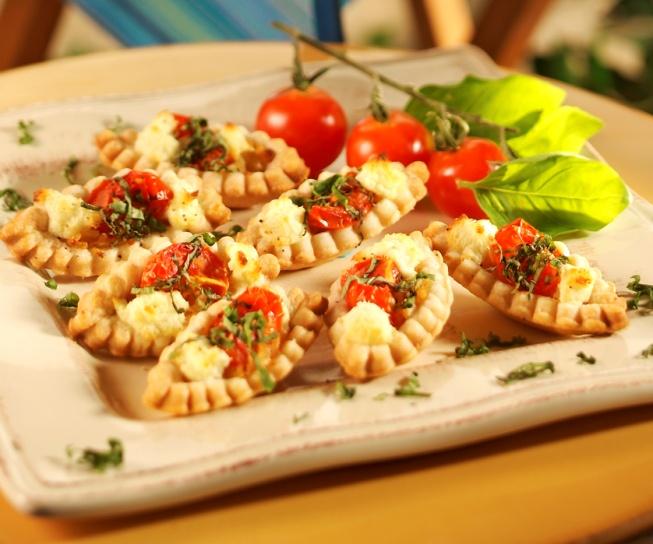 Tomato Basil Tartlets 1 15 ounce package piecrust dough 1 small onion, chopped 2 garlic cloves, minced 2 tablespoons butter 36 grape tomatoes 8 ounces goat cheese, crumbled 1/2 cup fresh basil, torn