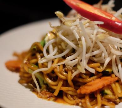 PAD KEE MAO Spicy stir-fried flat rice noodles with SRI-RA-CHA chilli sauce, basil, garlic, onion, peppercorn, zucchini, chinese broccoli