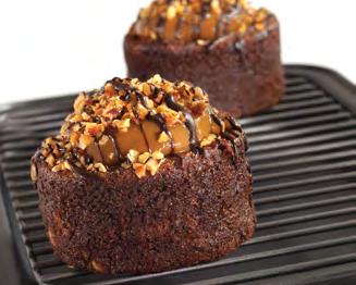 CHOCOLATE CARAMEL CRUNCH A flourless chocolate cake filled with crunchy almond bits, topped with creamy caramel and hazelnuts, drizzled with chocolate.