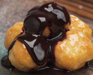 PROFITEROLES WHITE Cream puffs filled with chocolate cream and coated with vanilla cream.