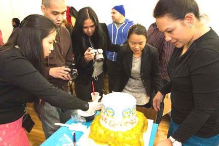 Adora Adora-Penn (rightmost) teaches the Jaycees how to stick edible paper with the Jaycees 50th year logo on the Golden Anniversary cake.