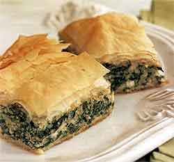3. In a medium bowl, mix together eggs, ricotta, and feta. Stir in spinach mixture. Lay 1 sheet of phyllo dough in prepared baking pan, and brush lightly with olive oil.