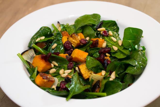 Roasted Butternut Squash over Spinach 2-2 1/2 cups diced butternut squash olive oil 2 shallots, peeled and quartered 8 garlic cloves, peeled kosher salt and pepper 4 cups spinach Handful pine nuts,