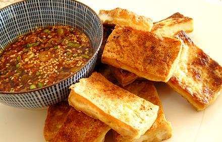 Spiced Fried Tofu 1 (16 ounce) package extra-firm tofu, drained and pressed 2 cups vegetable broth 3 tbs vegetable oil 1/2 cup all-purpose flour 1 tsp salt 1/2 tsp freshly ground black pepper 1 tsp