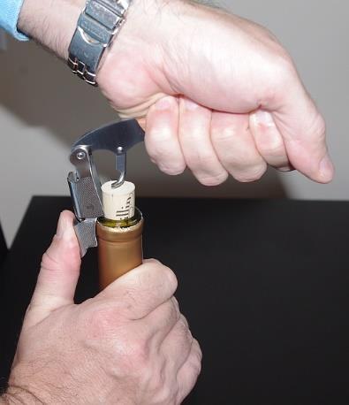 5) Lift the corkscrew up: Using your other hand, hold the fulcrum steady against the lip of the wine bottle.