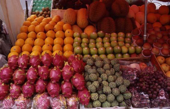 Fruit stand, Kǌnmíng. The large, red fruit on the front left are lóngguԁzi dragonfruit ; the even larger, spiny fruit in the middle back are liúlián durian. 8.5.