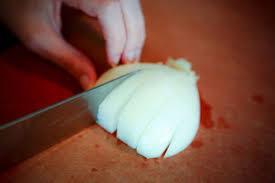 6. Make slices into the top of each half of the onion. a. Turn each half of the onion on its side to rest on the large flat surface. CAUTION: Keep your fingers out of the way of the knife. b.