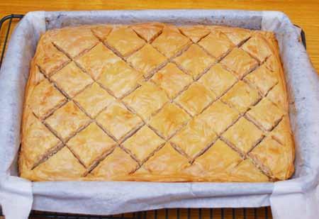 Remove the baklava from the oven and evenly pour the syrup over it, letting it settle into the grooves.