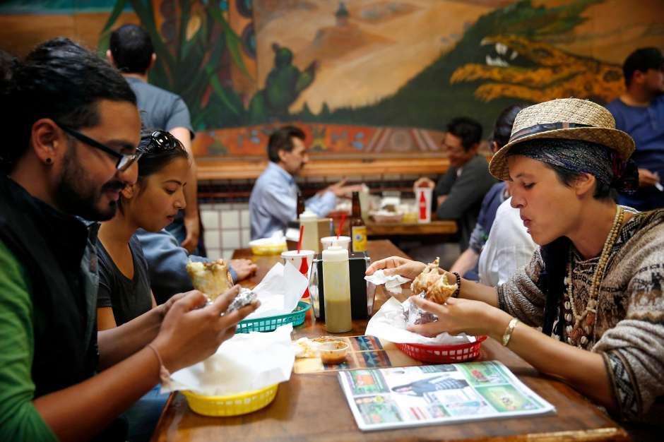 Ajesh Shah (l to r) of San Francisco and Julie Monin of Brazil enjoy burrito dorados during their lunch at La Taqueria on Wednesday, Sept. 10, 2014 in San Francisco.