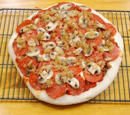 14 8 Here is my pizza, ready to go into the oven. I have my own order for the toppings: Sauce first, then Italian sausage, cheese, pepperoni, mushrooms, and finishing up with the caramelized onions.