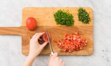 CUT AND JUICE In the meantime, dice the plum tomato. Juice the lemon and finely chop the curly parsley and mint.