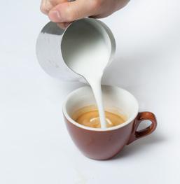 Keep the jug as close to the surface of the beverage as possible. Rock the jug side to side to release the heavier textured milk into the cup. This is how one creates shapes and patterns in the cup.