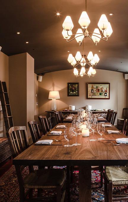The charming space features wood-beamed ceilings, whitewashed brick walls and cozy linen-tufted banquettes.