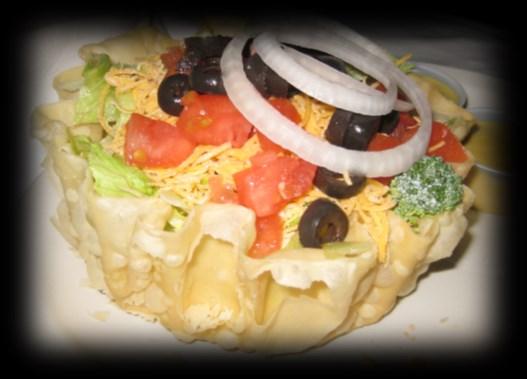 chicken over lettuce and served in an edible bowl with tomato, cheddar cheese, black olives and