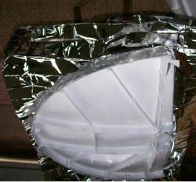 Coat the dish and/or reflective material with the spray adhesive, per instructions for a "permanent bond". Remember to note which side of the film will be facing up.