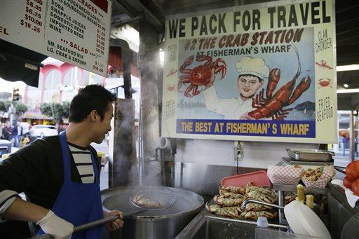 In this photo taken Tuesday, Nov. 10, 2015, Jinsen Zhao pulls an imported Dungeness crab from the Northwest out of a cooker at Fisherman's Wharf in San Francisco.