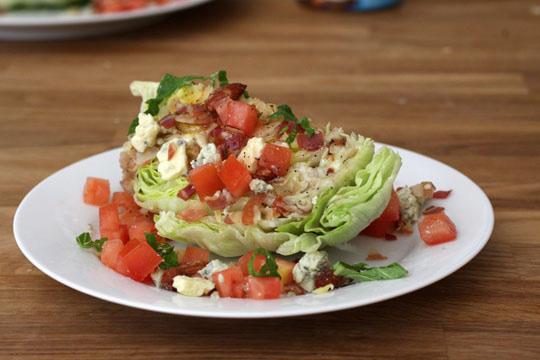 WEDGE SALAD w/ Blue Cheese Dressing 2 heads of iceberg lettuce, cut into quarters Blue cheese dressing 2 tomatoes, minced 2 green onions, chopped 1 cup crumbled blue cheese 1 cup cooked bacon,
