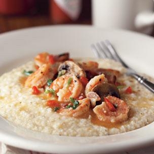 SHRIMP AND GRITS 8 cups water salt and pepper 2 cups stone-ground grits 6 tablespoons butter 4 cups shredded sharp cheddar cheese 2 pounds shrimp, peeled and deveigned 10 slices bacon, chopped 2 cups