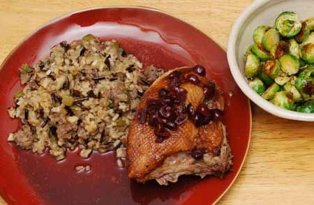 15 9 When the duck is done, let rest 5 minutes. Then plate with plenty of stuffing. Garnish the duck with the port/cranberry reduction sauce. Serve green vegetables on the side.