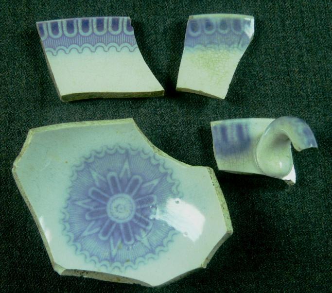 one cup and one saucer, decorated with lilac transfer prints of leaves. One shard has a lilac backstamp with OAK LE---- / C.