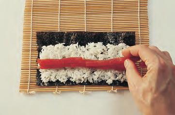(g) Holding the filling in place with the fingers, lift the corner of the mat with the thumbs and roll up.