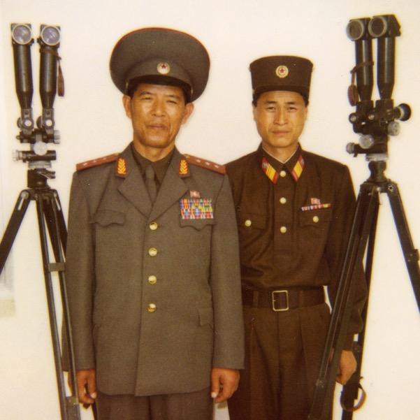 A North Korean colonel with a soldier on the DMZ, from where you see South Korea through binoculars.