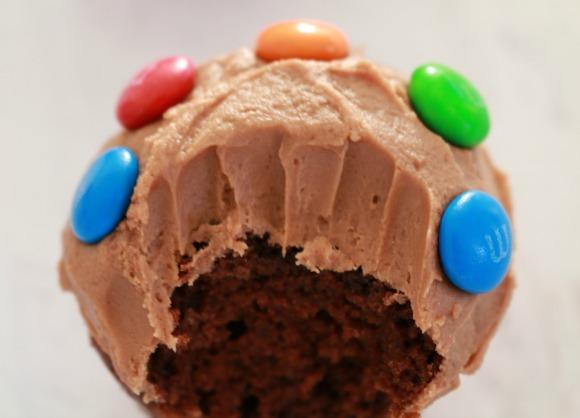 unsalted butter, softened 220g icing sugar 1 tsp vanilla extract 2-3 tbs milk, to loosen 100g Chocolate M&Ms to decorate Preheat oven to 170 C.