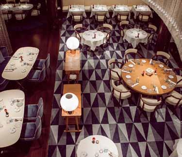 a long oval table and colourful leather chairs sit under delicate