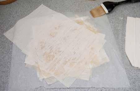 8 Place a phyllo sheet on your work surface (working on a piece of parchment paper can make the task a little easier), brush with melted butter, and arrange another sheet on top.