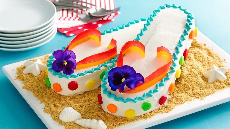 Flip Flop Cakes One box of cake mix, prepared according to instructions 1 container Whipped vanilla frosting Assorted gel food colors About 40 small round candy-coated fruit-flavored chewy candies
