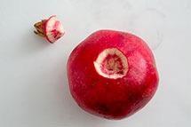 2 With a sharp knife, slice 1/4-inch off of the stem end of the pomegranate and place the